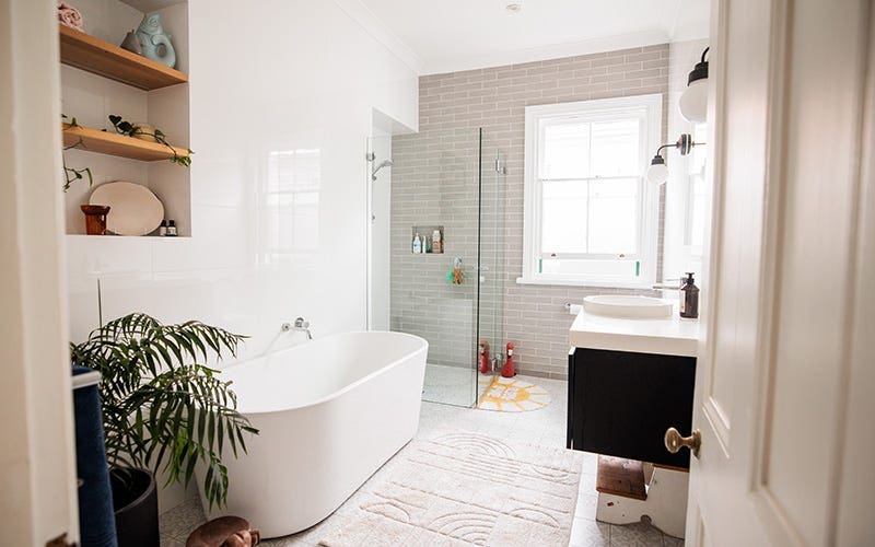 Une salle de bain lumineuse avec une baignoire blanche et une plante verte pour une atmosphère fraîche et accueillante.