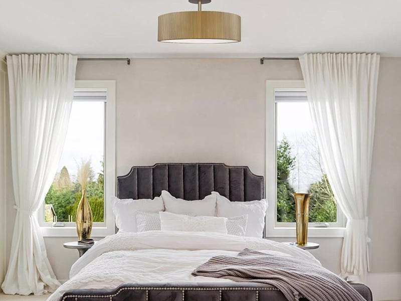 Elegant bedroom featuring a drum-shaped ceiling light between two windows
