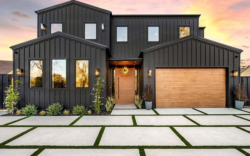 A modern home featuring sleek black siding and an attached garage, showcasing contemporary architectural design.