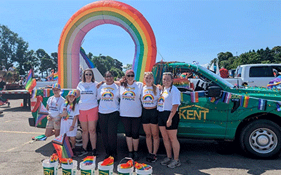 Community members gather in front of a vibrant truck adorned with a rainbow, promoting 2slgbtqia+ Pride charity run