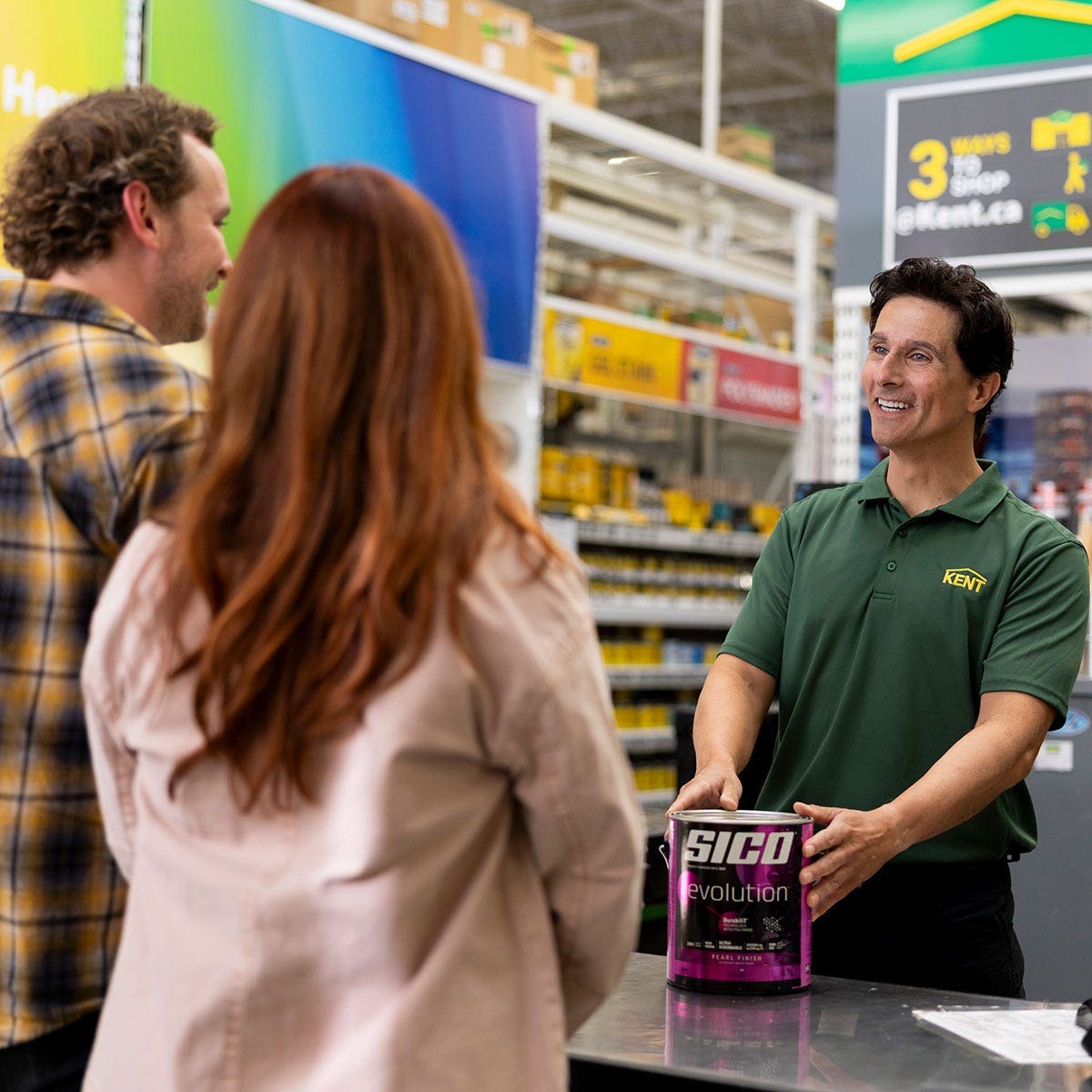 Store associate assisting customers with a paint purchase at a retail counter with a can of interior paint image